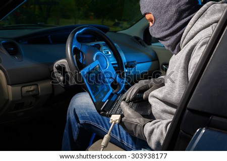Car thief stealing a car. Starting the car with a lap top