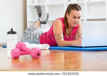 Young woman watching fitness videos and working out at her home.