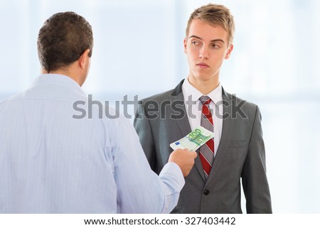Businessman offering bribe money to another businessman that is hesitant to accept it