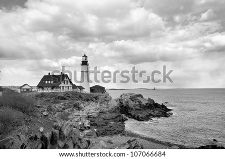 A famous New England Lighthouse along the rocky shore. Shown here in black and white.