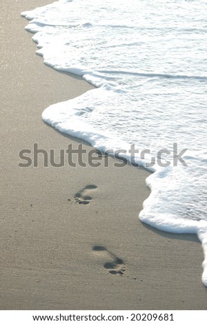 Two footprints along the ocean about to be washed away by the surf