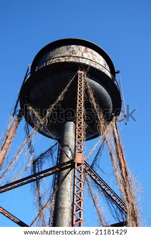 An old water tower unused and overgrown with weeds