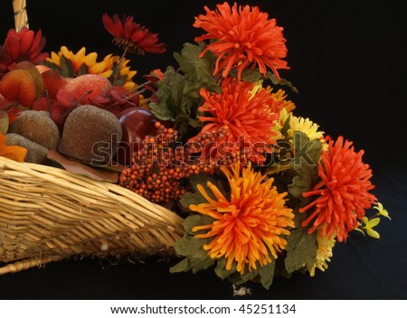 fall basket of flowers and fruit against a black background