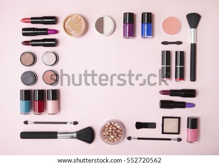 A collection of cosmetic beauty products arranged around a blank space on a pastel pink background, forming a page border