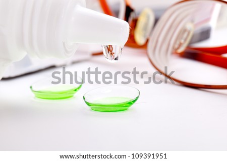 Close-up of green contact lenses in container with solution.