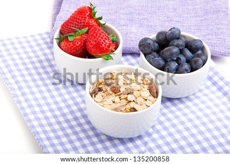 fresh blueberry, strawberries, corn flakes in the porcelain bowl,  on blue serviette.