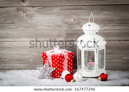 Burning lantern in the snow with christmas decoration, on wood background,