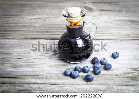blueberry syrup in glass bottle or mixture, on wooden background.
