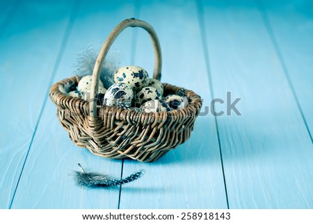 quail eggs in a wicker basket on blue wooden background