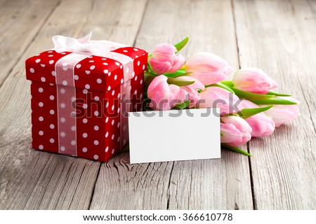beautiful tulips with red polka-dot gift box. happy mothers day, romantic still life, fresh flowers. on wooden background