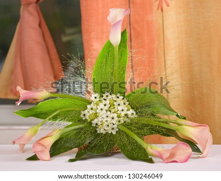 Pink flowers arrangements next to a orange curtain