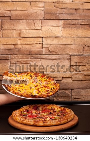 Two types of pizza next to a brown background