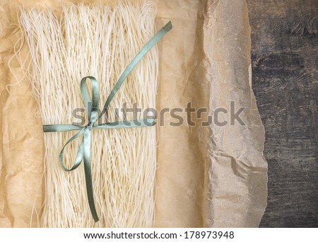 Chinese rice noodles,dry, in crumpled paper packaging with green ribbon, close-up