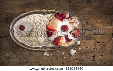 Dessert with strawberries, meringue and mascarpone, glass bowl on old metallic tray , wooden table