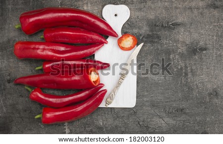 Long red fresh pepper,paprika on white cutting board with  antique knife , on old gray wooden background ,copy space