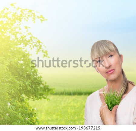 woman holds grass against backdrop of nature, ecology