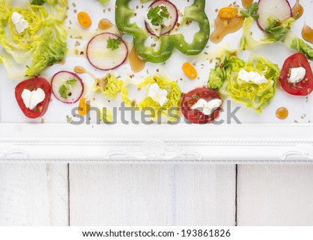 Chopped summer vegetables in tray with patterned border on white wooden table , top view