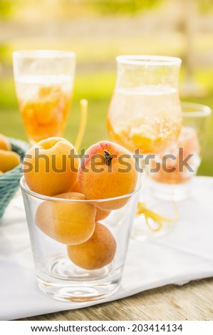 Ripe apricots in glass against  background of drinks and sunny garden