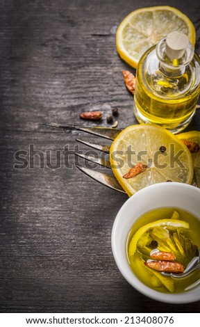 spice Oil with lemon and chili on old wooden table, food background with copy space