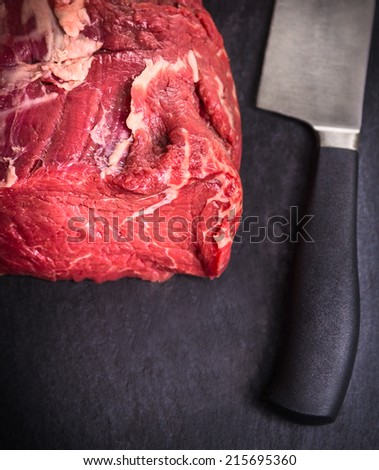 raw fillet of beef on slate table with  knife, top view