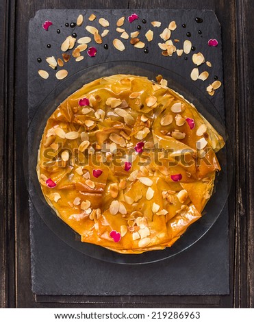 Pie of phyllo dough with syrup with rose water and almonds on dark slate background, top view