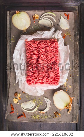 Raw ground beef on  wooden table with Spices and onion, top view