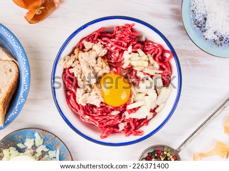 minced meat , bun soaked , slicing onions and egg in Bowl , mix for meat patties on white wooden background