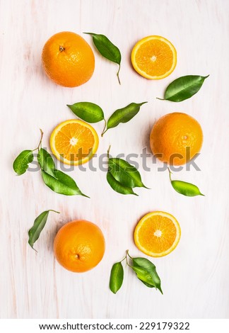 Oranges fruits composition with green leaves and slice on white wooden background, top view