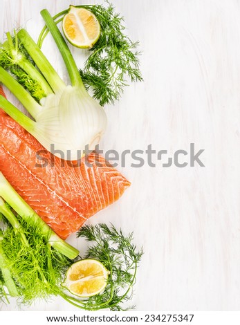 Raw salmon fillet with green herbs and lemon on white wooden, food background with place for text