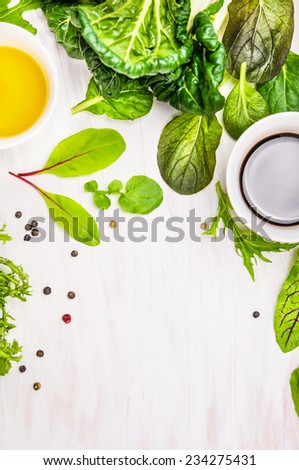 Salad leaves with dressingson white wooden table, food background with place for text