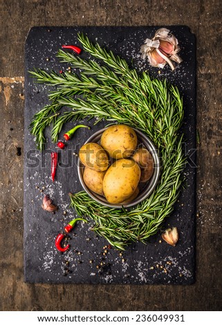 Potatoes with rosemary, garlic and spices, raw ingredients on slate and dark wooden background