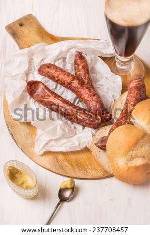 Snack with German smoked sausage,glass of beer and bread on white wooden background