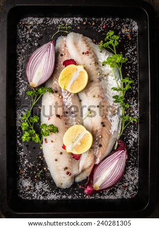 Raw fish with spices,herb,half onion,lemon and salt on dark backing tray background, top view