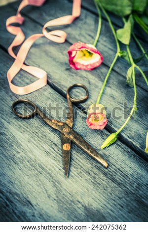 Blue Wooden table with flowers,ribbon and old scissors, florist background, toned