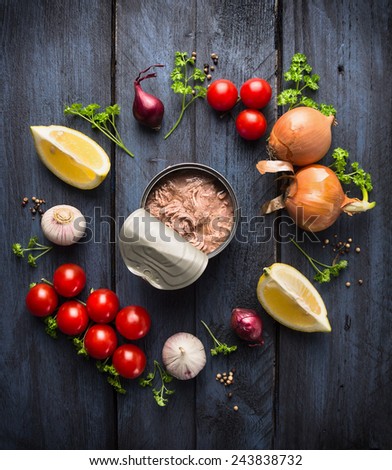 canned  tuna fish and ingredient for tomato sauce with herb, spices and lemon on blue wooden background, top view