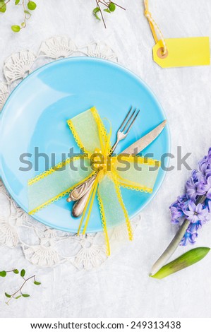 Blue plate with fork,knife and yellow table decoration, top view