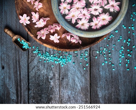 Spa background with sea salt, bowl ,flowers and water, top view