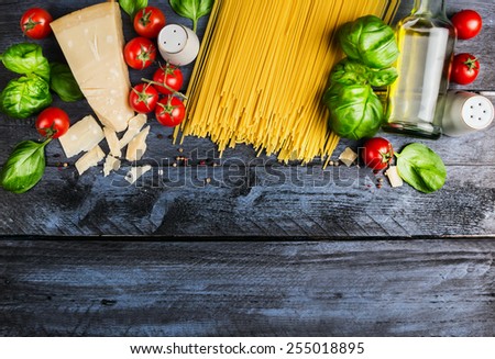 Raw spaghetti with tomatoes, basil,parmesan and oil, cooking Ingredients  on blue rustic wooden background, top view, place for text