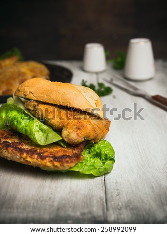 roll with schnitzel on gray wooden background , fast food