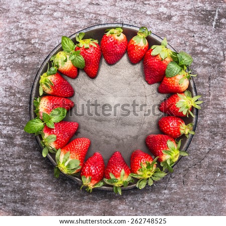 Fresh ripe strawberries in plate on gray wooden background, food frame, top view with place for text