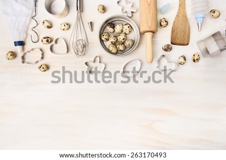 Easter bake tools with quail eggs and biscuit cutter on white wooden background, top view, place for text