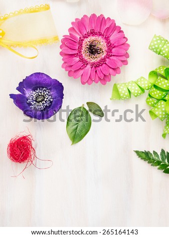 Florist background with flowers and accessories on white wooden background, top view, place for text