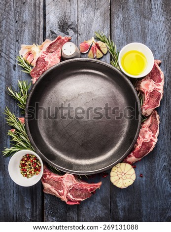 Empty plate with raw lamb loin chops meat , oil, herb and spices on  blue wooden background, top view