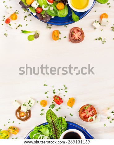 salad with tomatoes, greens, dressing and feta cheese in blue plate on white wooden background, top view frame
