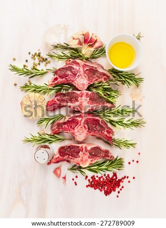 Raw lamb  chop cutlet with oil , rosemary and garlic on white wooden background, top view