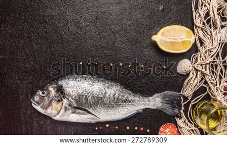 raw dorado fish with fishing net on black stone background, top view, place for text
