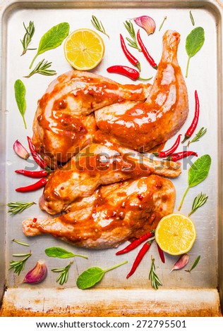 raw chicken legs with red spicy sauce, sage and lemon on old bake tray, top view, close up