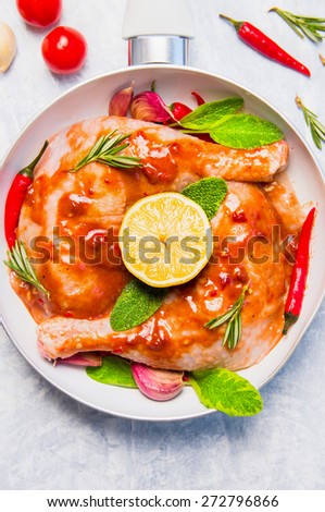 raw chicken legs with red spicy sauce, preparation in white  frying pan, top view, close up