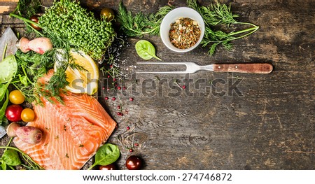 Raw salmon fillet with fresh seasoning, spices and fork on rustic wooden background, top view, banner for website with cooking concept