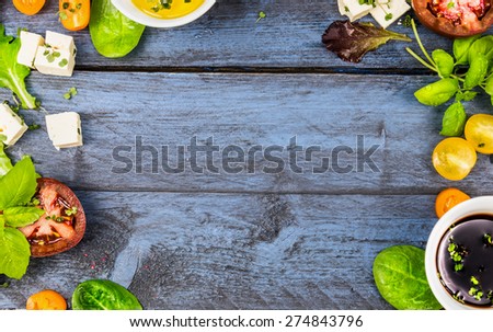 Food frame with salad ingredients: oil,vinegar, tomatoes, basil and cheese on blue rustic wooden background, top view, horizontal